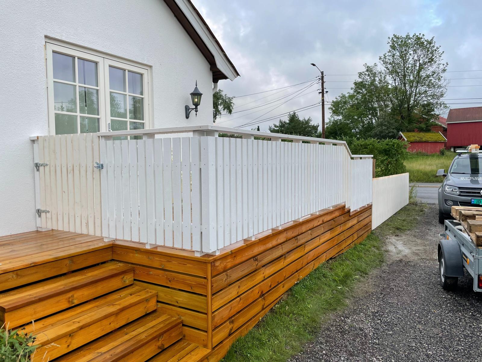 Terrasse med hvitt rekkverk og trapp i tre